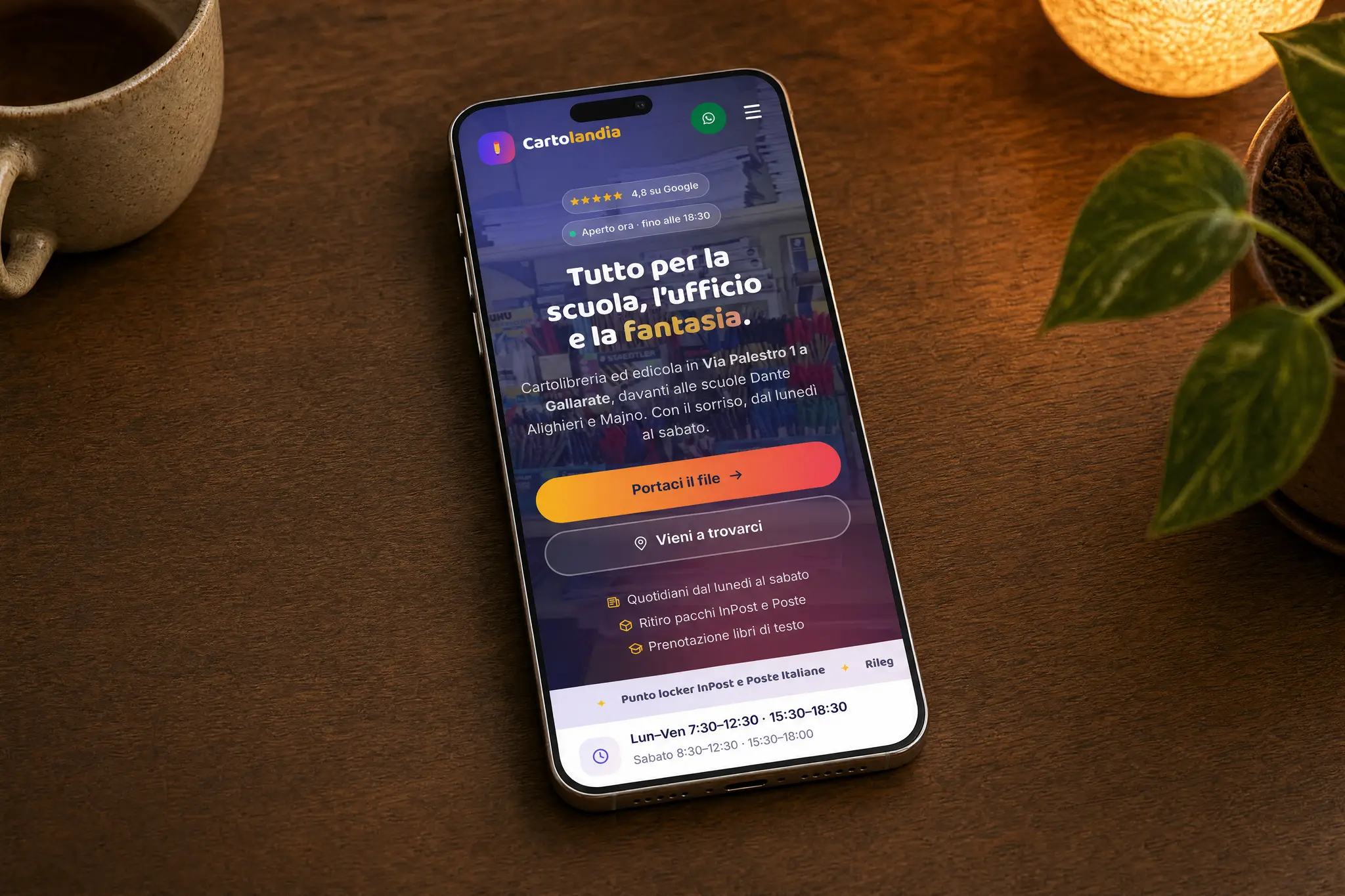 Il sito di Cartolandia su un telefono posato sulla scrivania di legno, ripreso dall'alto: si leggono «Tutto per la scuola, l'ufficio e la fantasia», il 4,8 su Google, l'orario di chiusura e i due tasti per mandare il file o venire in negozio.